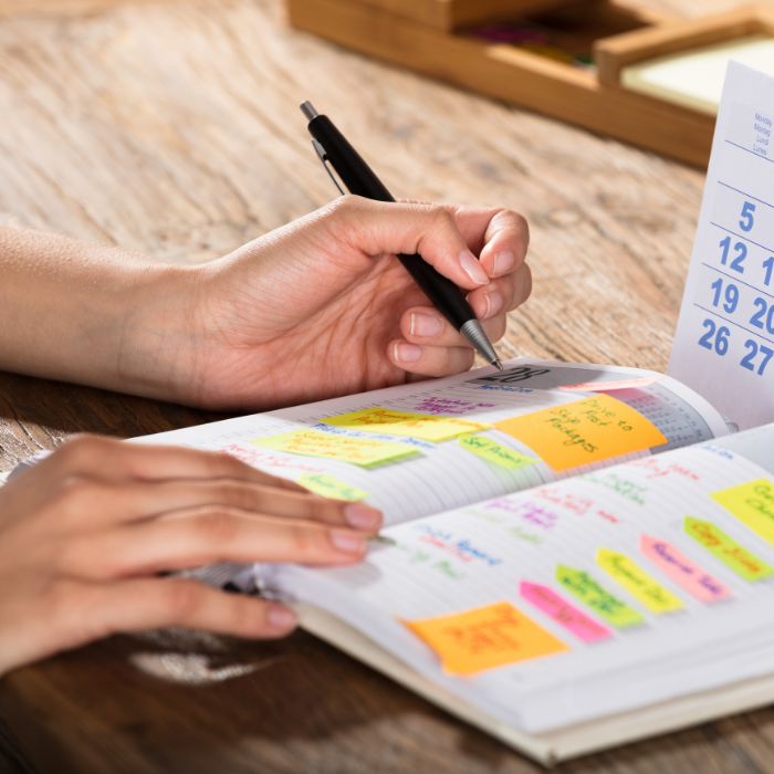Make it Work image of woman writing in calendar using colored sticky notes