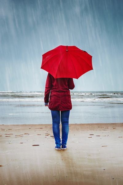 Person with red umbrella on rainy beach