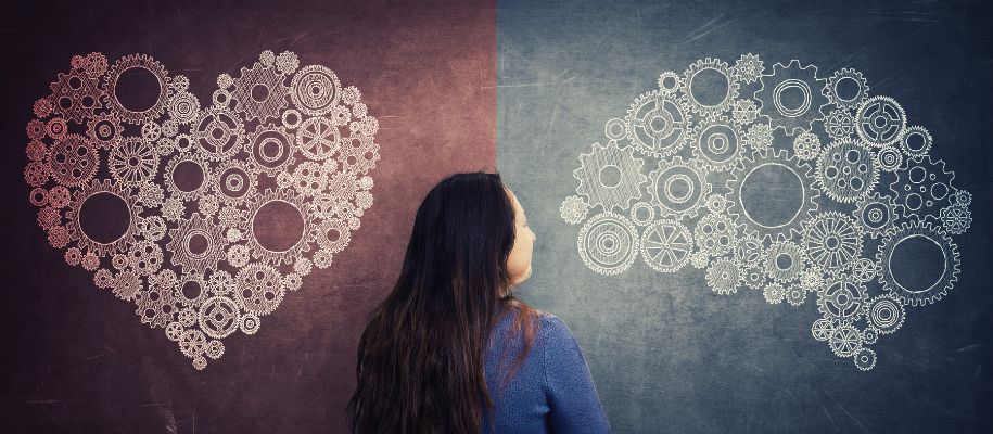 Woman contemplating heart and brain gear diagrams.