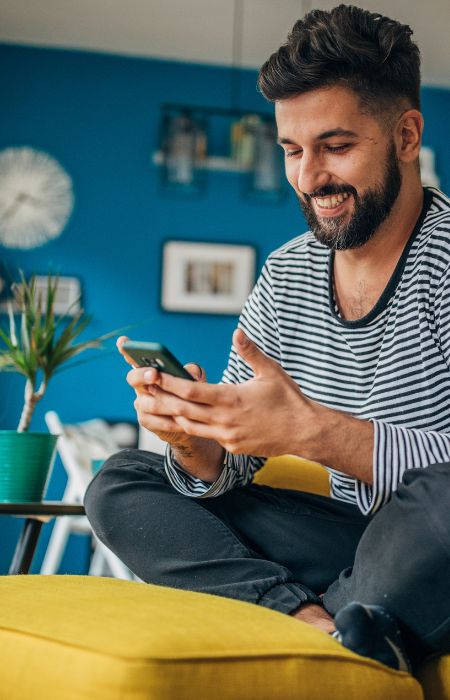 Man smiling and using smartphone at home