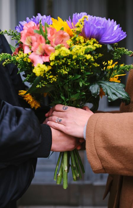 Couple holding a colorful bouquet of flowers.