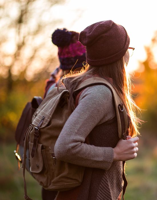 Two hikers with backpacks at sunset outdoors.