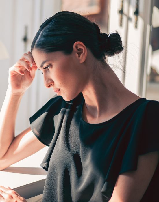 Woman in black shirt looking thoughtful indoors