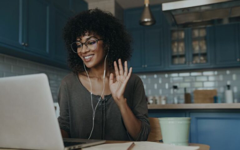 Smiling woman video calling on laptop at home.